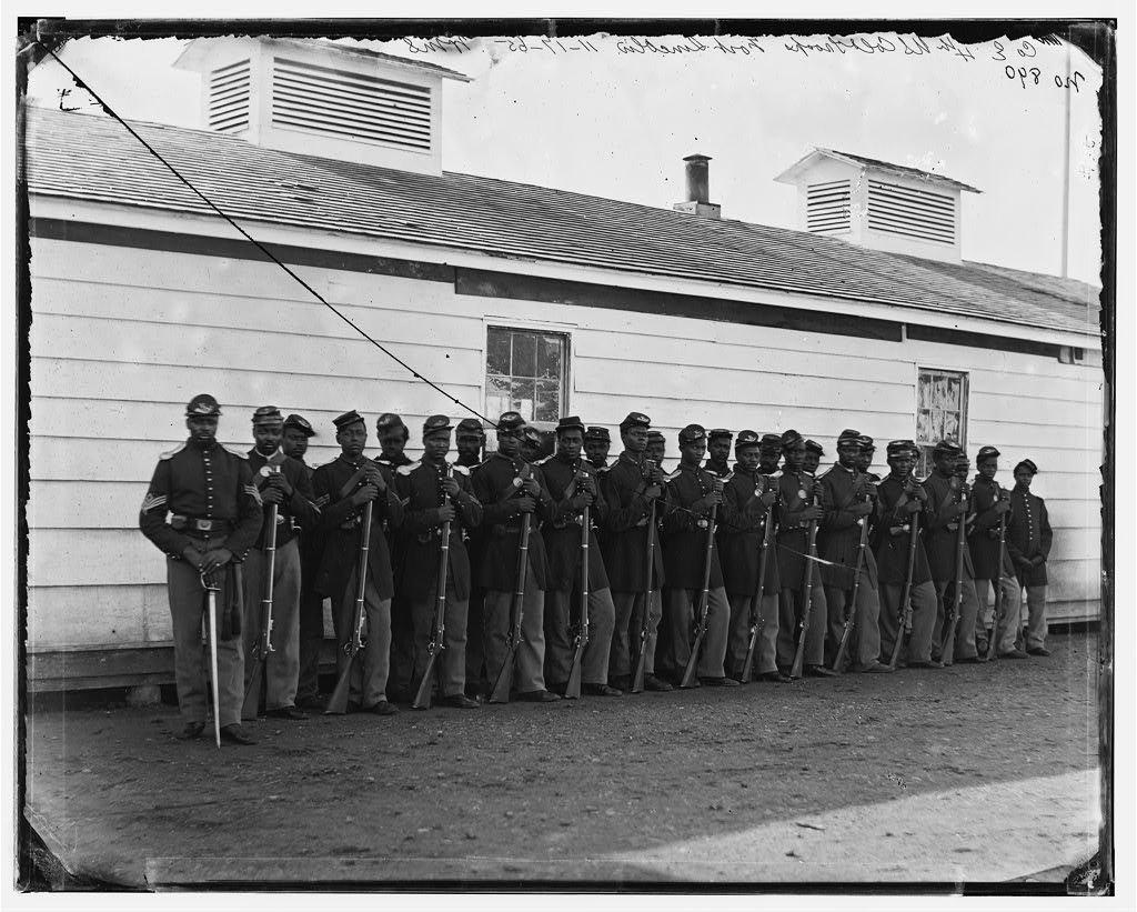 Photograph of soldiers of Company E, 4th U.S. Colored Infantry standing in two lines with rifles at Fort Lincoln, District of Columbia.